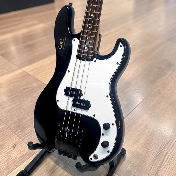Black electric bass guitar on a stand in a music store