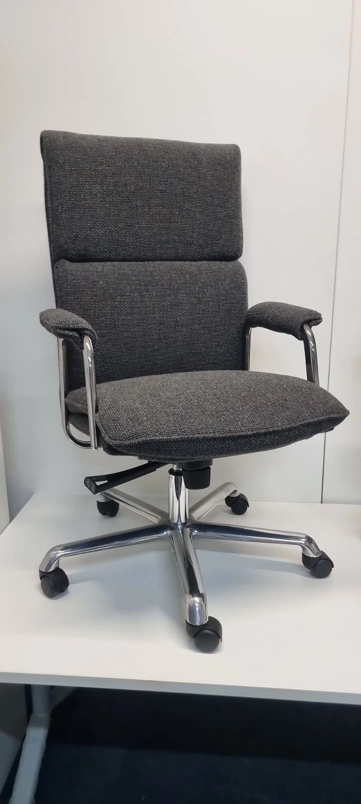Gray office chair with a high backrest on a white surface.